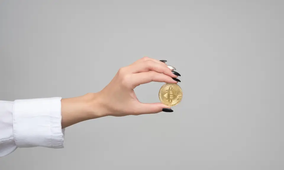 Hand holding a gold Bitcoin coin